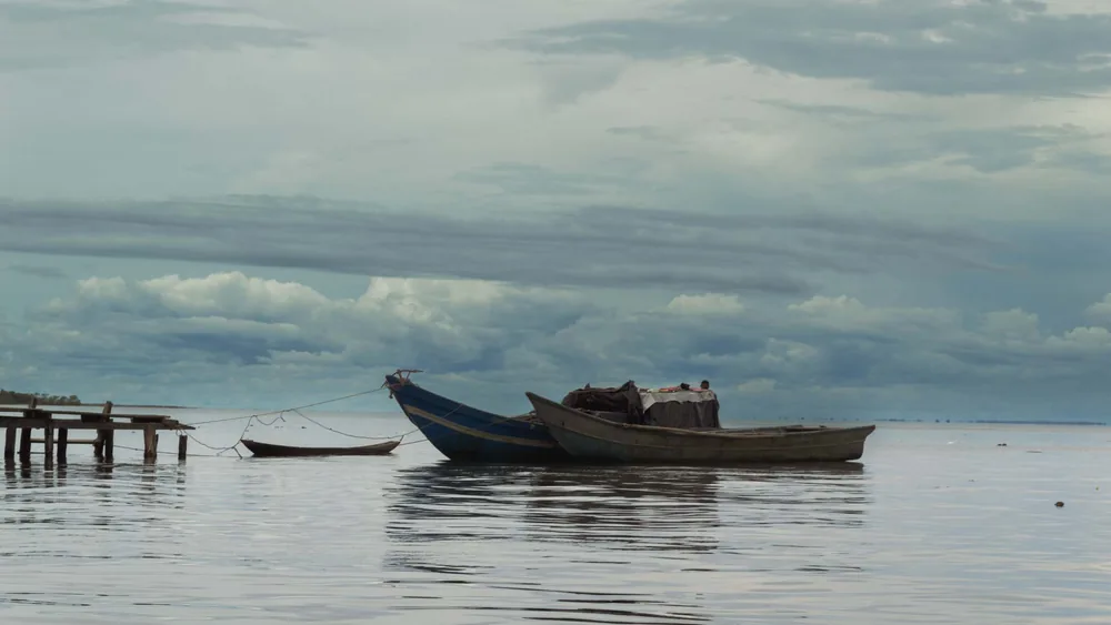 Canoas de madera amarradas junto a un muelle rústico bajo un cielo nublado